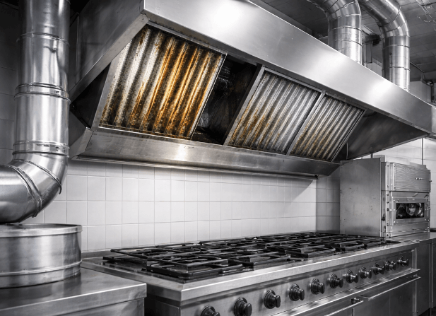 Fettablagerungen in der Abluftanlage einer gewerblichen Küche mit verschmutzten Fettfiltern und Abluftventilator.